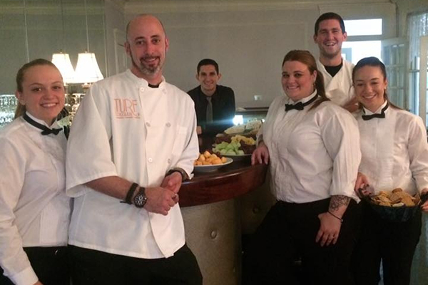 catering staff standing at a table in tuxes and chef whites